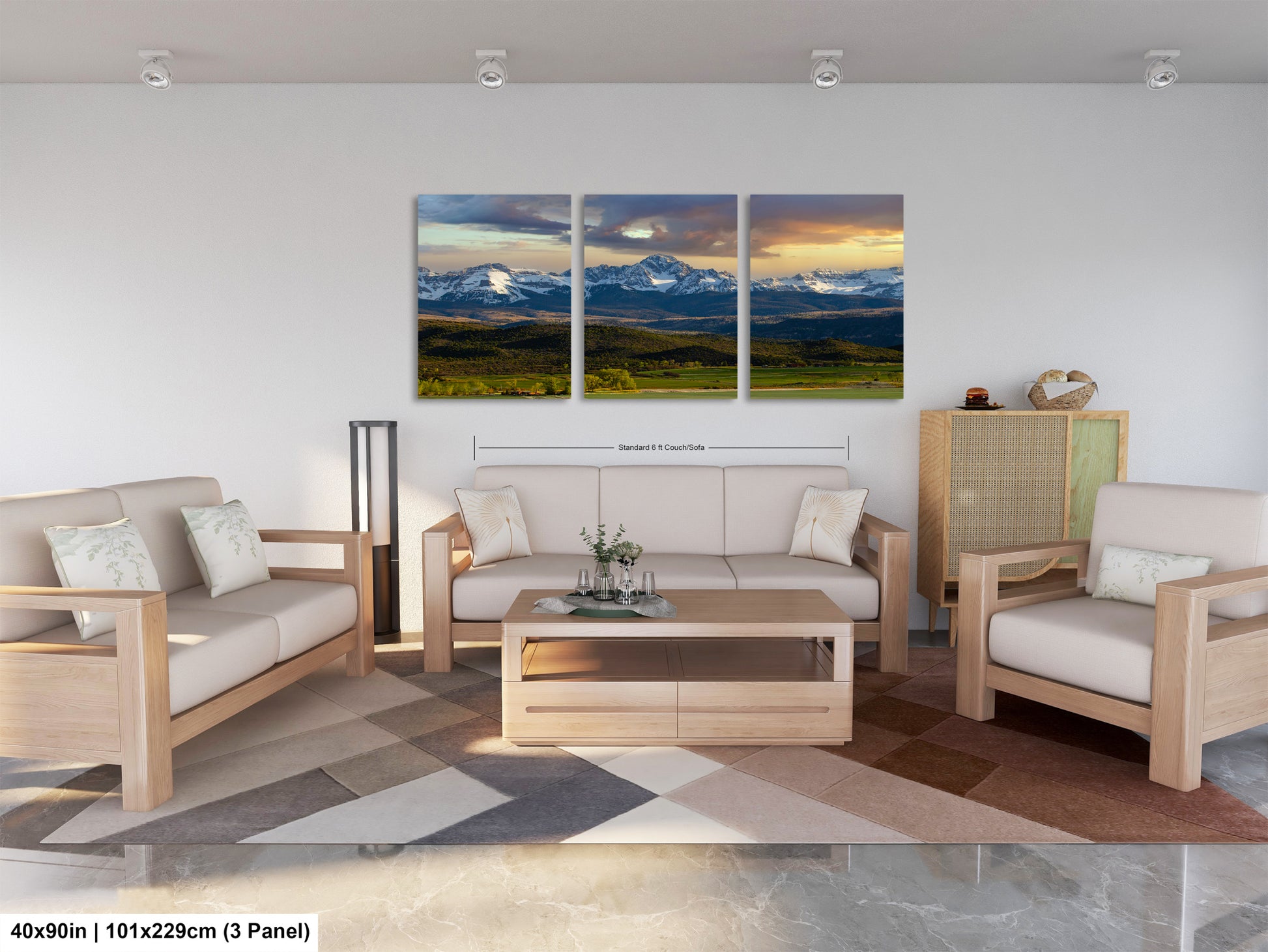The image is a modern living room with a large, three-panel landscape painting hanging on the wall. The painting depicts a scenic mountain range with a cloudy sky. The room is furnished with a sofa, two chairs, and a coffee table, creating a comfortable and inviting atmosphere.