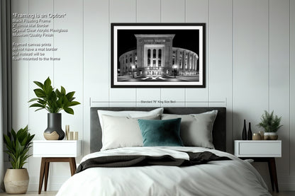 a bedroom with a large framed black and white photograph of a stadium on the wall above a bed with white bedding.
