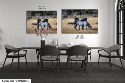 a dining room table with chairs and two pictures of horses on the wall