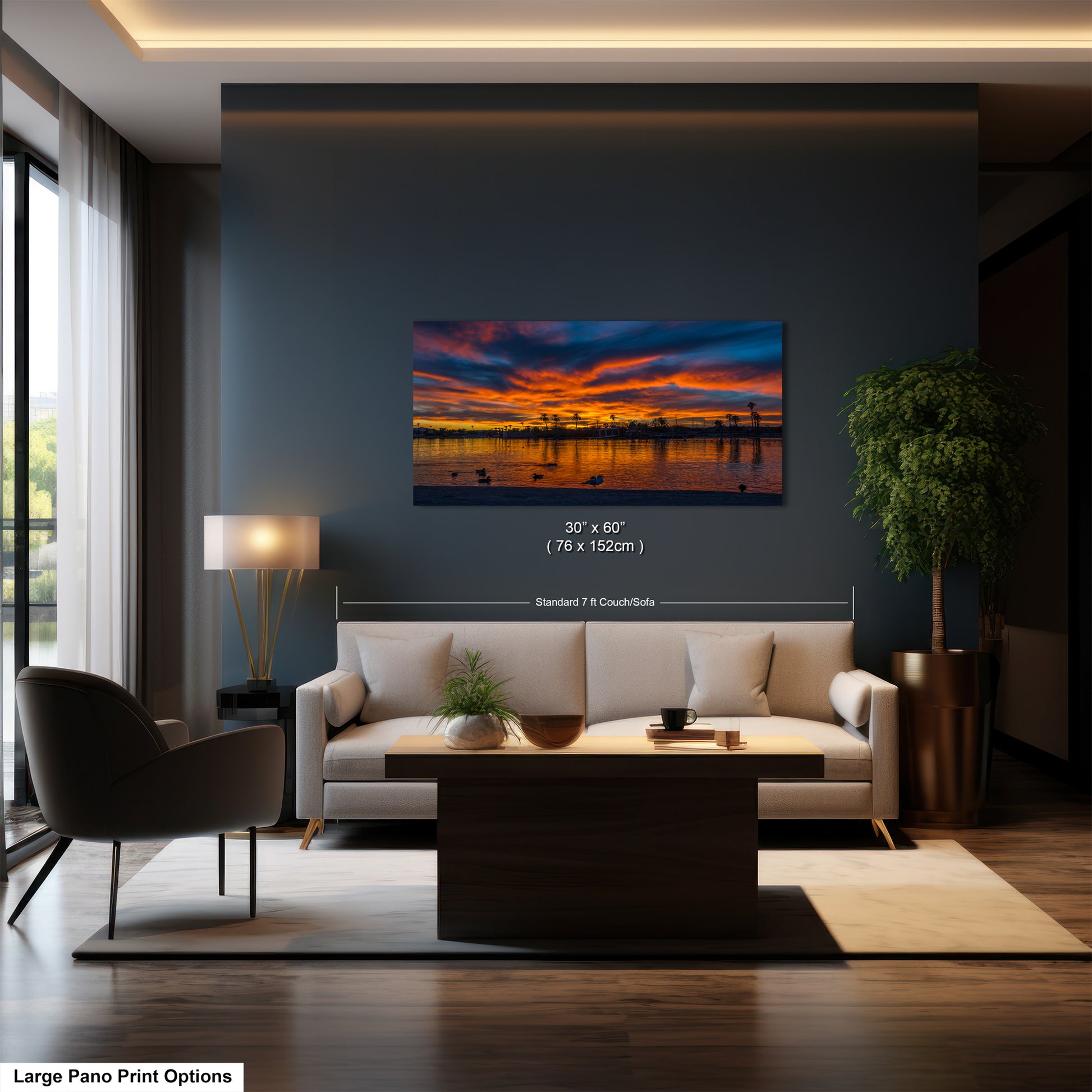 A modern living room with a large sofa, a coffee table, and a painting of a sunset over a body of water hanging on the wall.