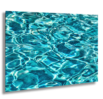 The image is a close-up of a body of water, likely a pool or a lake, with a beautiful, shimmering surface that reflects the light in a mesmerizing pattern. The water appears to be crystal clear and has a vibrant blue-green hue, creating a captivating visual effect.
