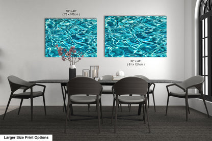 a modern dining room with a large table and six chairs. Two large paintings of water are displayed on the wall above the table, creating a serene and calming atmosphere.