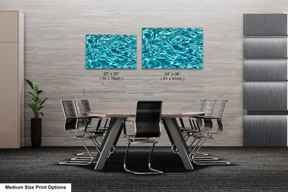 a modern office space with a large wooden table surrounded by black chairs. Two framed prints of water are displayed on the wall above the table, creating a serene and calming atmosphere.