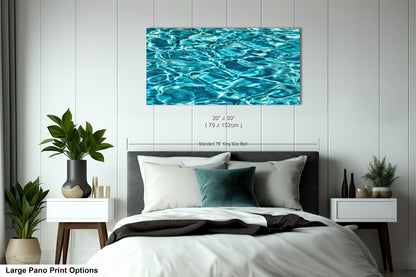 A large bedroom with a bed, nightstands, and a large framed print of a water-themed image hanging on the wall above the bed.