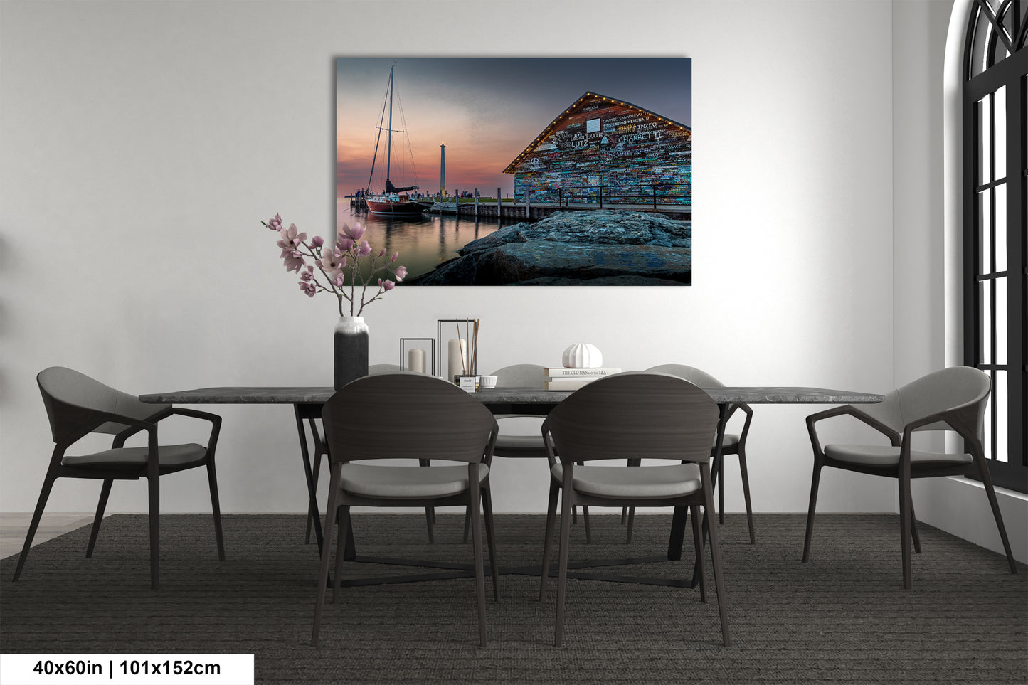a serene scene of a boat docked at a pier, with a building featuring a colorful facade in the background. The photograph is framed and hung on a wall, creating a focal point in the room.