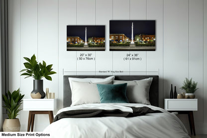 a bed with a white comforter and two pictures on the wall above it