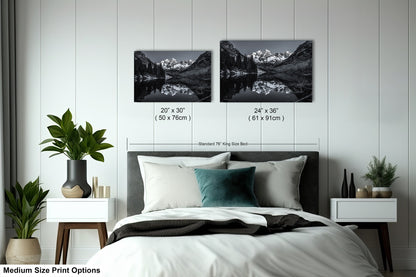 a bed with a white comforter and two black and white pictures on the wall