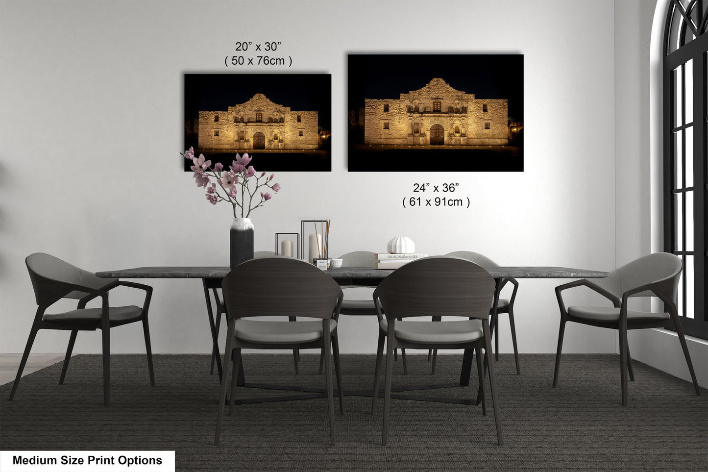 a dining room with a table and chairs, and two framed photographs of a building, likely a historic landmark, hanging on the wall above the table.