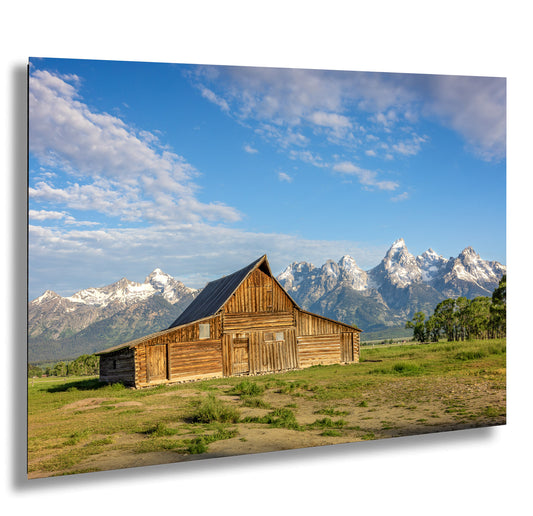 a barn in a field with mountains in the background