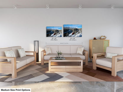 a modern living room with a white sofa, two chairs, and a coffee table. There are two framed landscape photographs hanging on the wall above the furniture.