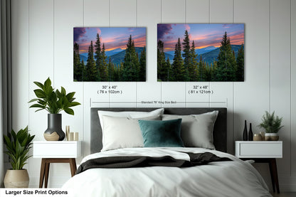 a bedroom with a large bed and two framed landscape photographs hanging on the wall above it. The photographs depict a scenic mountain landscape with pine trees and a colorful sunset sky.