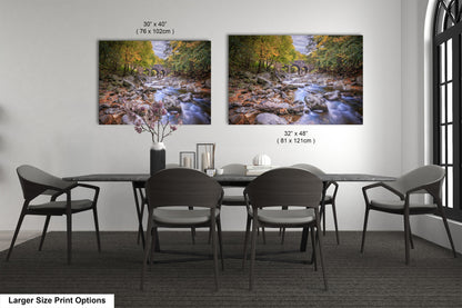a dining room table with four chairs and two pictures on the wall
