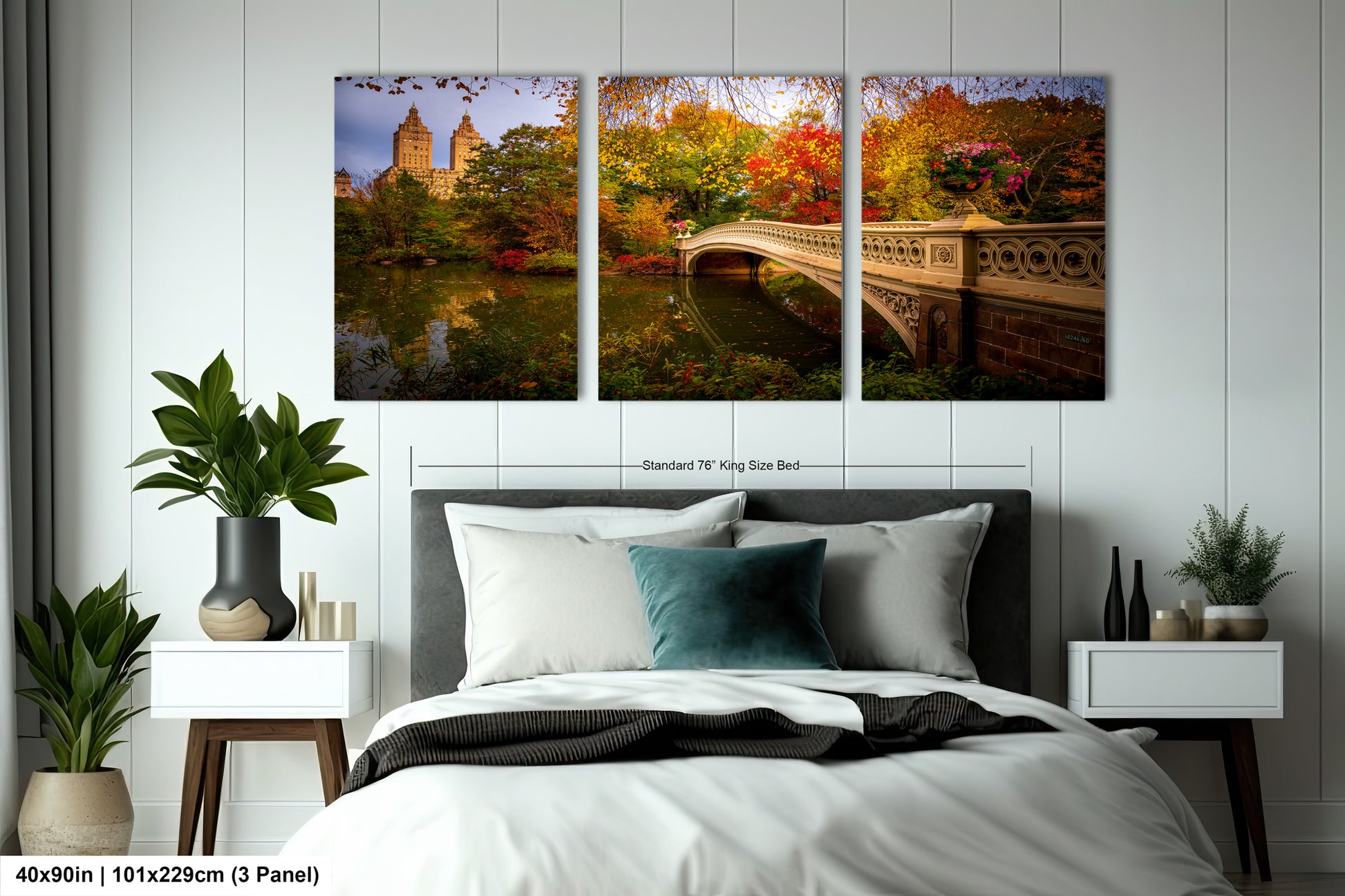 The image is a bedroom with a large bed, nightstands, and a potted plant. Above the bed, there is a large painting depicting a scenic view of Central Park in New York City, with a bridge and trees in the background.