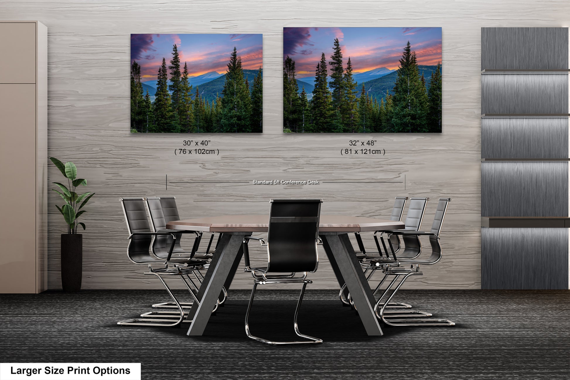 a modern office space with a large wooden table surrounded by black chairs. Above the table, there are two framed landscape photographs depicting a scenic mountain view at sunset. The photographs are of different sizes, with one being larger than the other. The office space has a minimalist design with gray walls and a gray carpet.