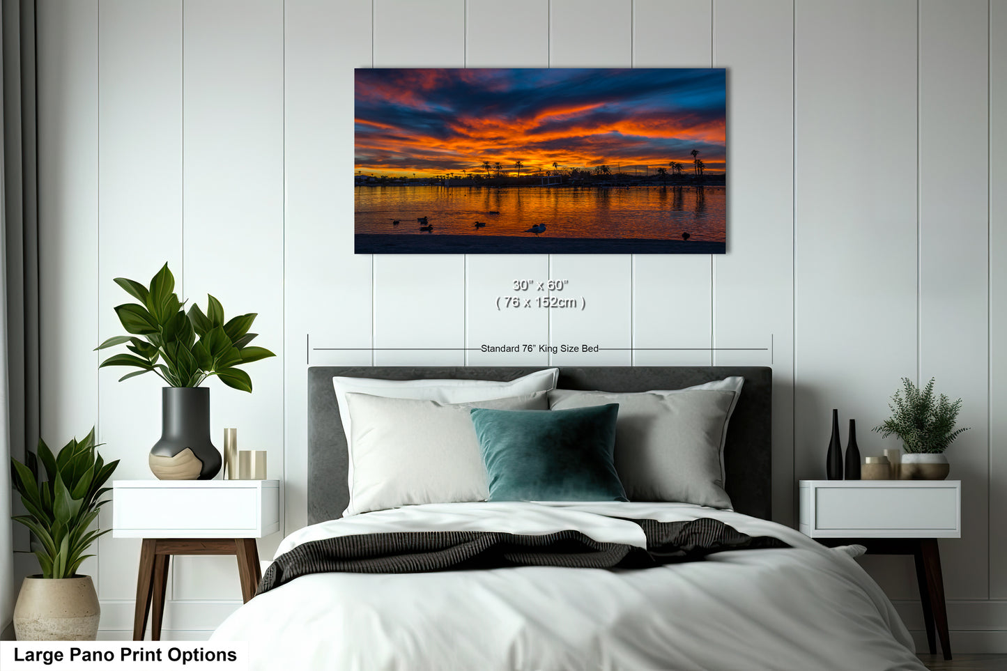 A large pano print depicting a serene sunset over a body of water, with silhouetted trees and birds in the foreground.