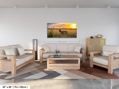 a living room with a large, framed picture of a deer in a field at sunset hanging on the wall.