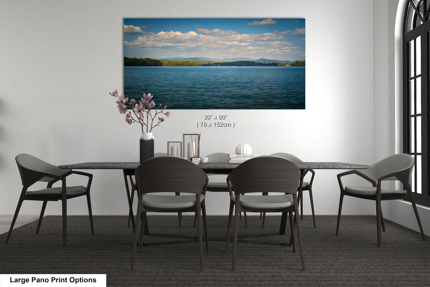 A large pano print depicting a serene lake surrounded by mountains, with a cloudy sky above.