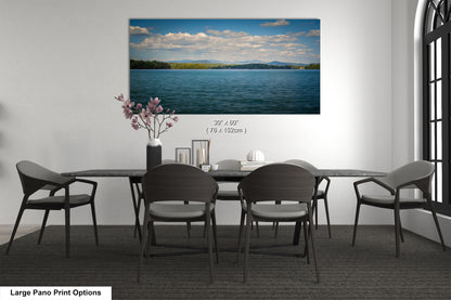 A large pano print depicting a serene lake surrounded by mountains, with a cloudy sky above.