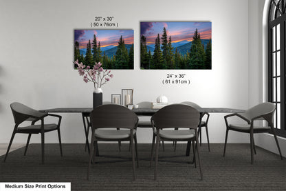 a dining room with a large dining table surrounded by six chairs. Above the table, there are two framed landscape paintings depicting a mountain range at sunset. The paintings are of different sizes, with one being larger than the other. The paintings are hung on the wall above the table, creating a focal point in the room.