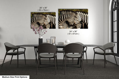a dining room table with four chairs and two pictures of zebras on the wall