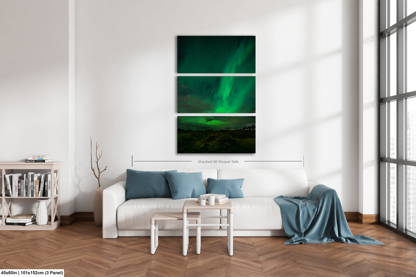 A modern living room with a white sofa, a coffee table, and a bookshelf. Above the sofa is a large canvas print depicting a night sky with the aurora borealis.