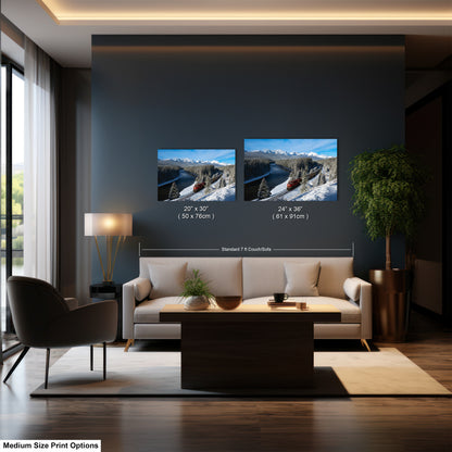 a modern living room with a large sofa, a coffee table, and a potted plant. There are two framed landscape photographs hanging on the wall, one depicting a snowy mountain scene and the other showing a river. The wall is painted in a dark color, and the furniture and decor create a cozy and inviting atmosphere.