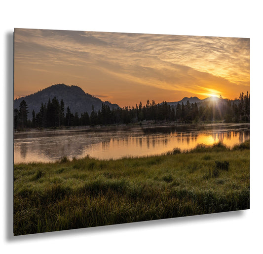 the sun is setting over a lake with mountains in the background