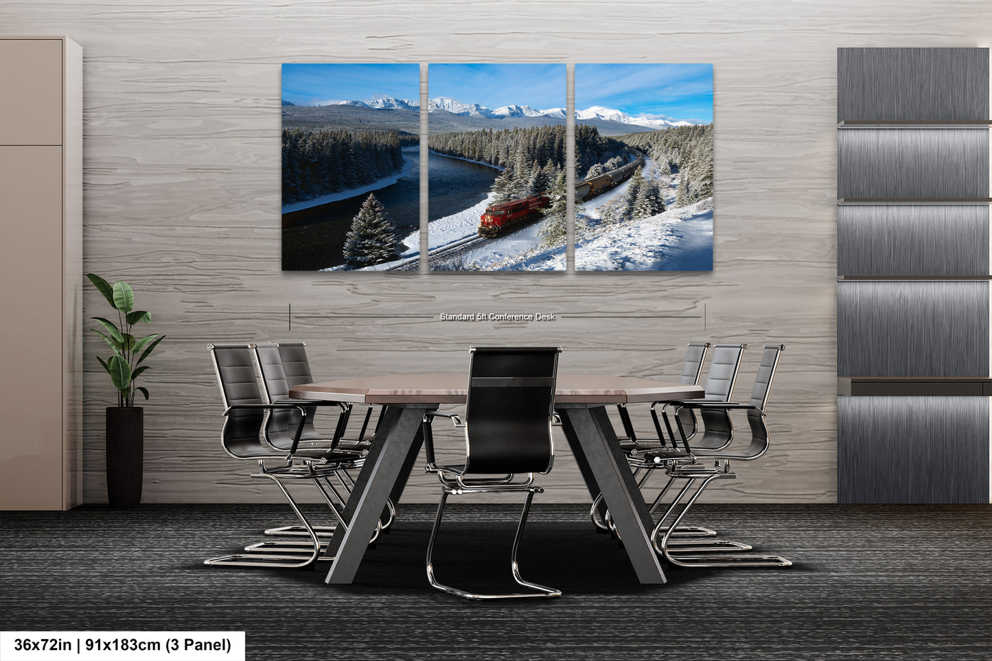 A modern office space with a large, three-panel landscape painting depicting a snowy mountain scene with a train passing through it. The painting is mounted on a gray wall above a wooden table surrounded by chairs.
