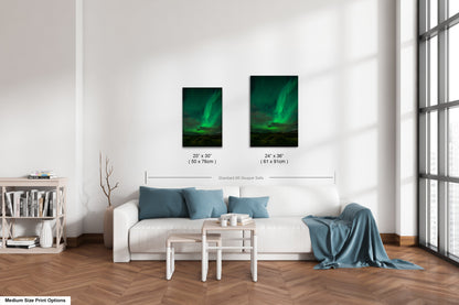 a living room with a white sofa, a coffee table, and a bookshelf. There are two framed pictures of the northern lights hanging on the wall above the sofa.