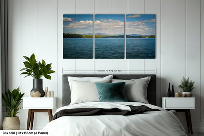 A bedroom with a large bed, nightstands, and a large wall art depicting a serene lake scene with mountains in the background.
