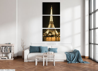 a living room with a white couch and three pictures of the eiffel tower