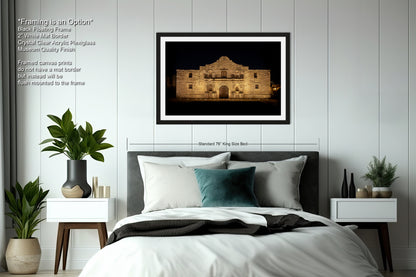 a bedroom with a large framed photograph of a building, a bed with white bedding, and various decorative elements such as potted plants and vases.