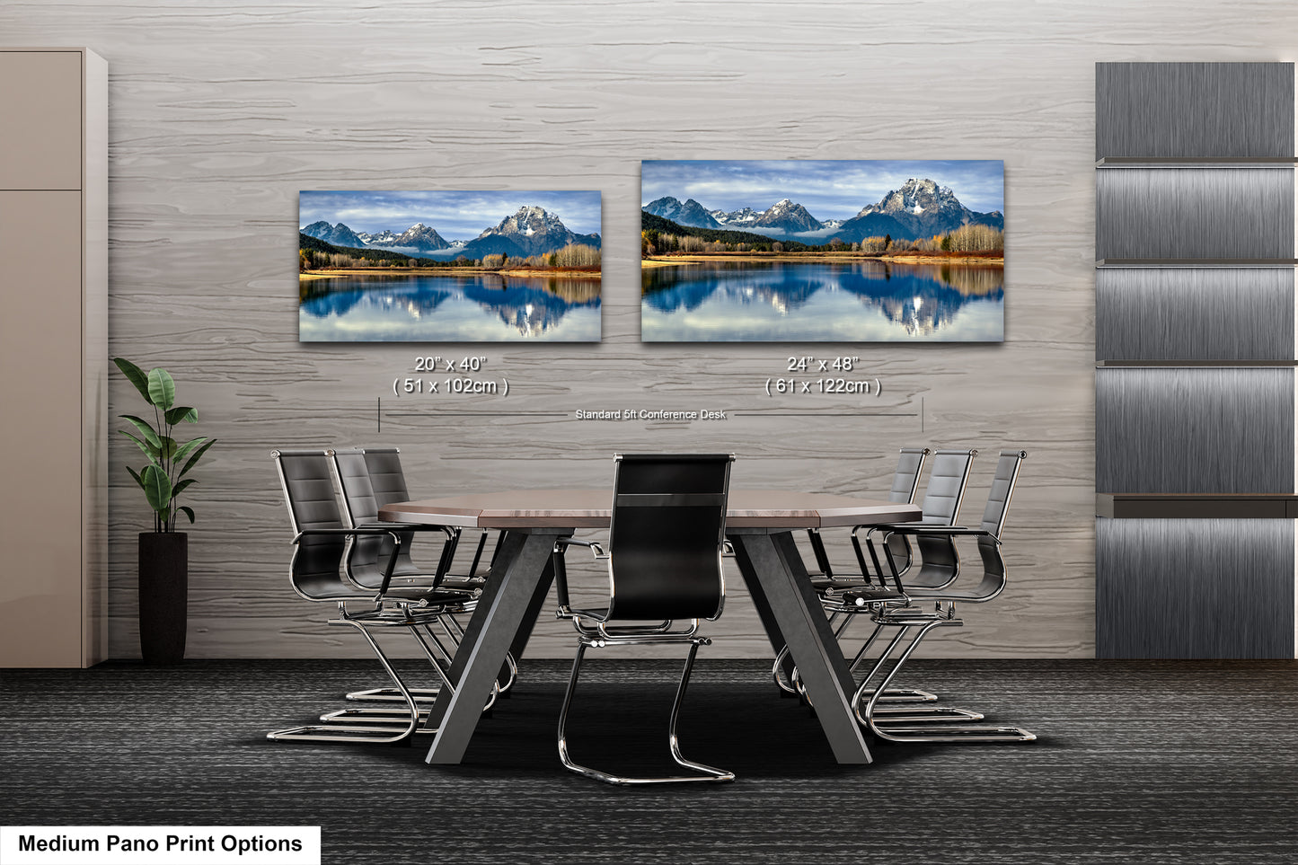a modern office space with a large wall displaying two framed landscape paintings depicting a serene mountain lake scene. The paintings are hung at eye level, creating a focal point in the room. The office space includes a wooden table surrounded by chairs, and a potted plant is visible in the corner.