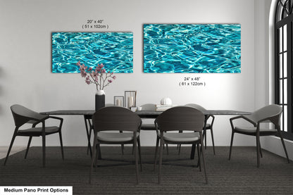 a modern dining room with a black table and chairs, and two large framed prints of water on the wall above the table.