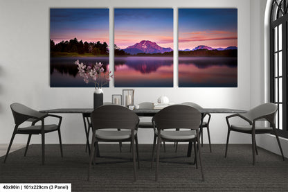 a dining room table with four chairs and three paintings on the wall