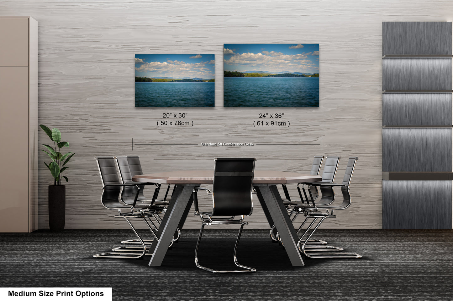a modern office space with a large wooden table surrounded by black chairs. Two framed landscape photographs are displayed on the wall above the table, depicting a serene lake and a cloudy sky. The table and chairs are positioned in front of the wall, creating a focal point in the room.