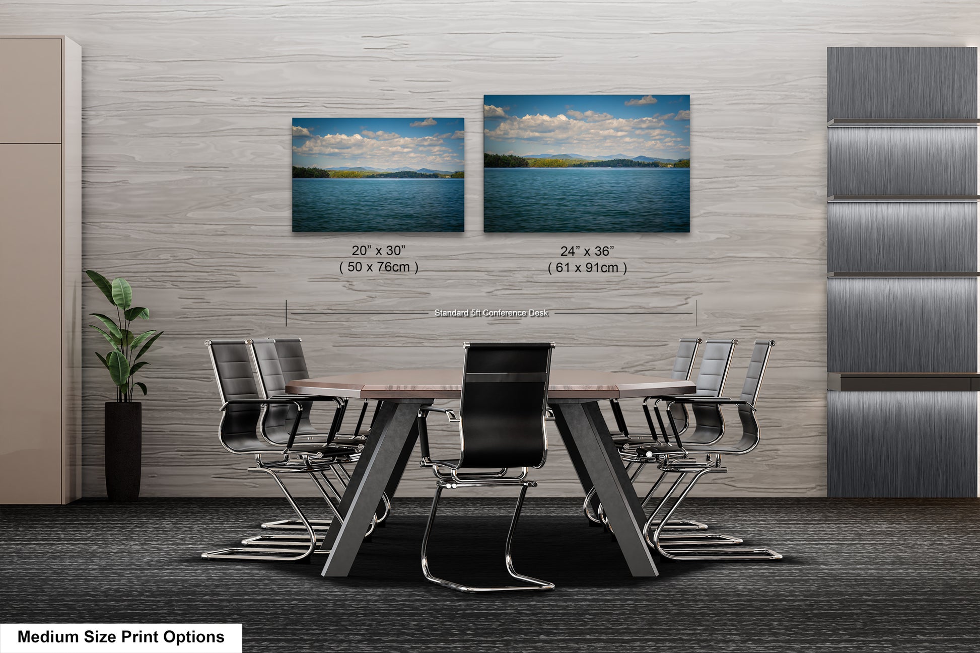 a modern office space with a large wooden table surrounded by black chairs. Two framed landscape photographs are displayed on the wall above the table, depicting a serene lake and a cloudy sky. The table and chairs are positioned in front of the wall, creating a focal point in the room.