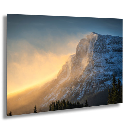 a mountain covered in snow and clouds at sunset
