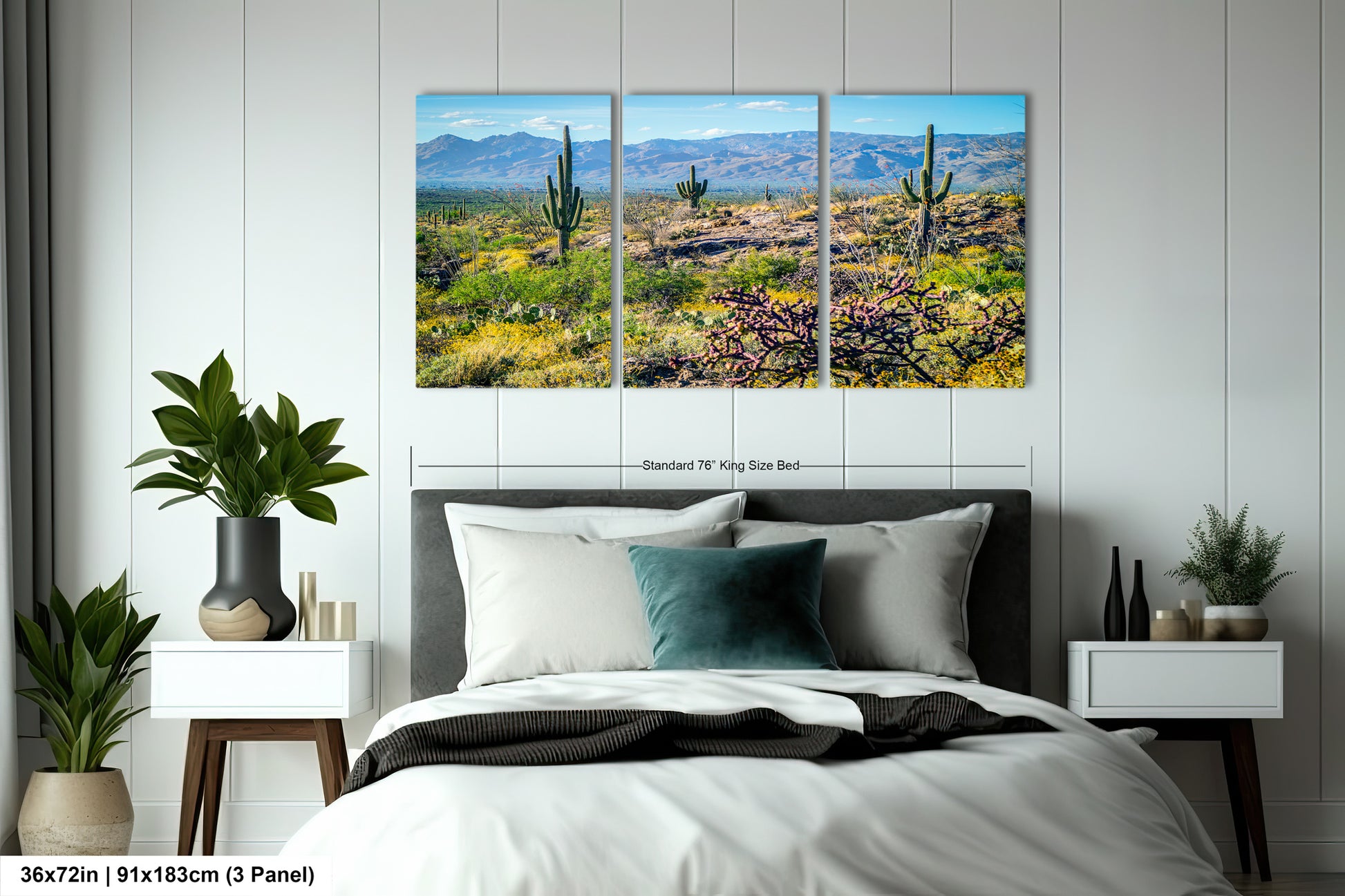 A bedroom with a large bed, nightstands, and potted plants. Above the bed is a large canvas print depicting a desert landscape with cacti and mountains in the background.