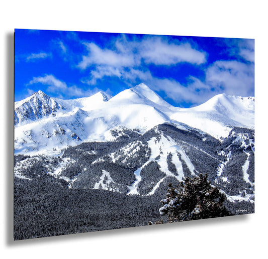 a mountain range covered in snow under a blue sky