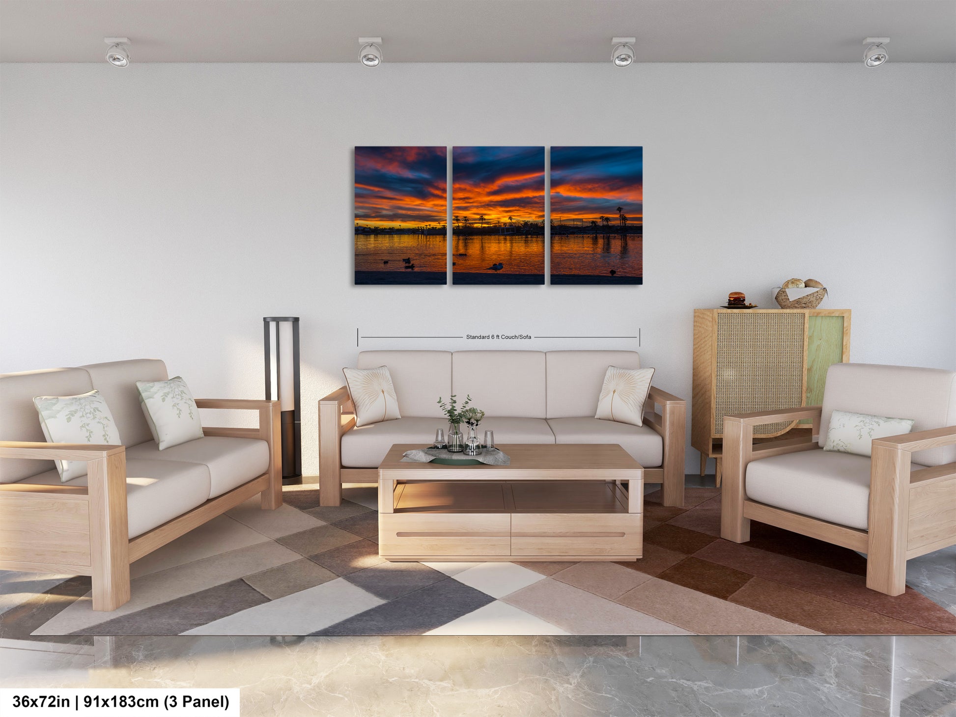 A modern living room with a large, three-panel landscape painting depicting a sunset over a body of water. The painting is hung on the wall above a wooden coffee table, which is surrounded by two white couches and a matching chair. The room has a minimalist and clean design, with a neutral color palette and a geometric patterned rug on the floor.