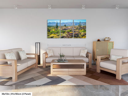 A modern living room with a large, three-panel landscape painting depicting a desert scene with mountains in the background. The room is furnished with a sofa, two armchairs, and a coffee table, creating a comfortable and inviting atmosphere.