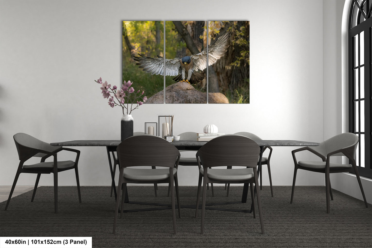 a modern dining room with a large painting of a bird of prey, possibly a hawk, on the wall above a table with chairs. The painting is divided into three panels, creating a dynamic and visually engaging display. The room has a minimalist and clean design, with a gray color scheme and a vase of flowers on the table adding a touch of nature to the space.