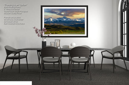 a modern dining room with a large framed landscape painting hanging on the wall above a black dining table surrounded by six chairs.
