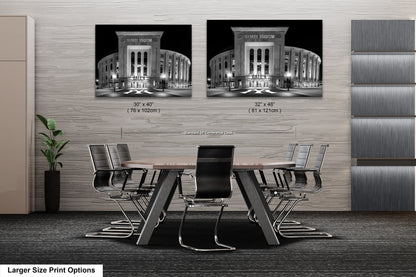 a modern office space with a large wooden table surrounded by black chairs. Two framed black and white photographs of Yankee Stadium are displayed on the wall above the table.