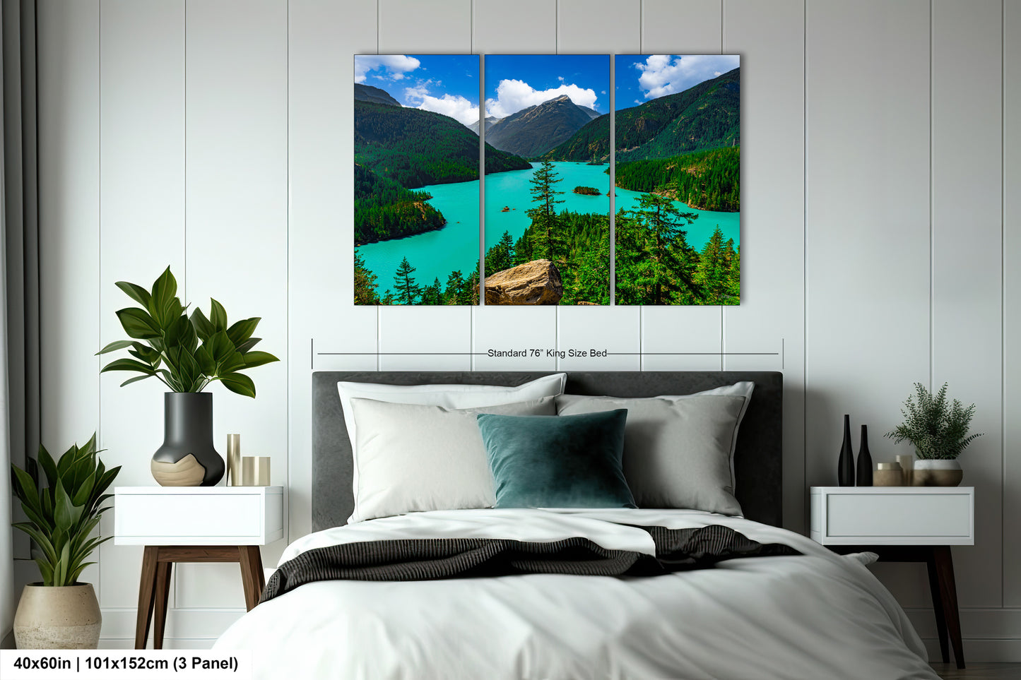The image is a bedroom with a large, high-quality, three-panel landscape painting hanging on the wall above the bed. The painting depicts a scenic mountain lake surrounded by lush green forests.