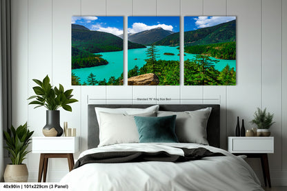 The image is a large bedroom with a bed, nightstands, and a large wall art depicting a scenic landscape with mountains, a lake, and trees.