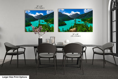 two large landscape paintings hanging on a wall, depicting a scenic mountain lake surrounded by lush green forests.