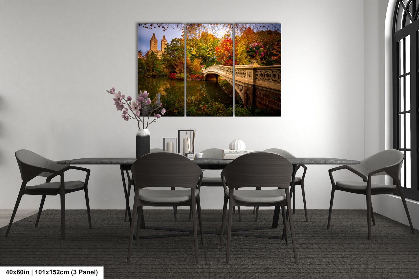 The image is a modern dining room with a large, colorful painting of a bridge and trees hanging on the wall above a black table with six chairs.